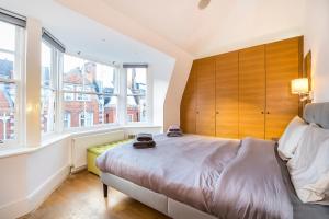 Schlafzimmer mit einem großen Bett mit einem Kopfteil aus Holz in der Unterkunft Lux Duplex near Oxford St in London