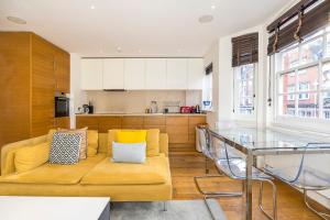 a living room with a yellow couch and a glass table at Lux Duplex near Oxford St in London