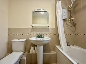 La salle de bains est pourvue d'un lavabo, de toilettes et d'une baignoire. dans l'établissement Super Apartment next to Bicester Village Sleeps 4, à Bicester