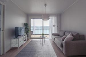a living room with a couch and a television at Pramea Apartments Kultaniemi in Kuopio