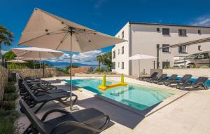 uma piscina com cadeiras e um guarda-sol em Luxury Apartments Villa Lučica em Malinska