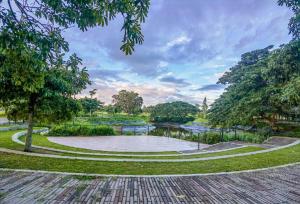 a park with a pond in the middle of it at Stanford Suites, South Forbes - Standard Room with pool in Silang