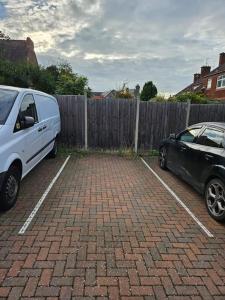 Ein weißer Van und ein schwarzer Wagen stehen auf einem Parkplatz. in der Unterkunft Stylish 2 Bedroom Semi-Detached House in Leicester in Leicester