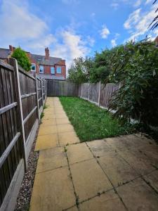 a backyard with a fence and a sidewalk next to a yard at Stylish 2 Bedroom Semi-Detached House in Leicester in Leicester