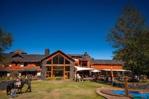 a large building with people and horses in front of it at Patagonia Lodge in Las Trancas