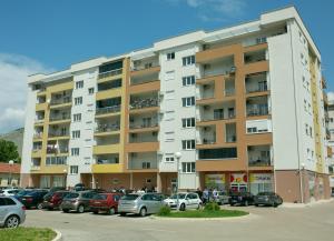 a parking lot with cars parked in front of a building at Apartman SUNCE in Trebinje