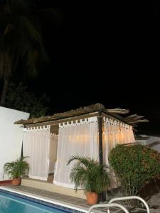 a building with white curtains next to a swimming pool at Casa de los Colores in Honda