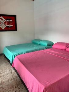 two beds in a room with pink and blue at Casa de los Colores in Honda