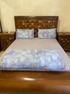 uma cama com cabeceira em madeira e almofadas em Residence Adja Binta Kane Sour em Dakar