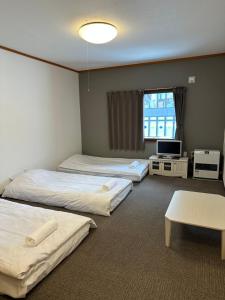 a hotel room with three beds and a tv at Pension Berg in Niseko