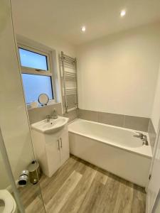 a white bathroom with a tub and a sink at Eden Stay in Morecambe