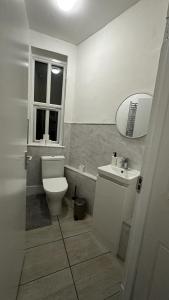 a bathroom with a toilet and a sink and a mirror at Wandsworth Guest Rooms 64 in London