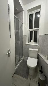 a bathroom with a toilet and a shower and a window at Wandsworth Guest Rooms 64 in London