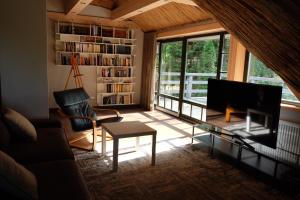 sala de estar con sofá, TV y estante para libros en SVILPJI Lakeside Retreat House in a Forest with all commodities en Amatciems