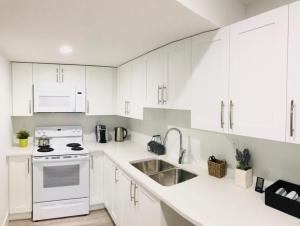 a kitchen with white cabinets and a white stove top oven at Homelike & cozy suite in Langley