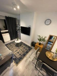 a living room with a couch and a clock on the wall at Studio apartment in London, Bethnal Green in London