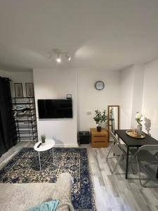 ein Wohnzimmer mit einem Tisch und einem TV an der Wand in der Unterkunft Studio apartment in London, Bethnal Green in London