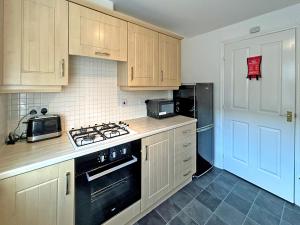 a kitchen with wooden cabinets and a black stove top oven at Hindmarsh Apartment in Ashington