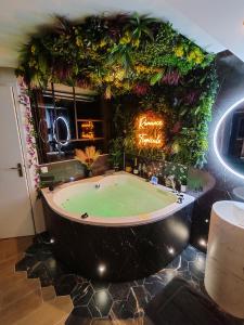 un bagno con una grande vasca con piante sul muro di Le Quai Amiénois - Romance Tropicale - SPA Romantique ad Amiens