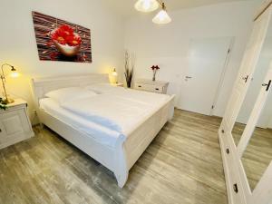 a bedroom with a white bed and a painting on the wall at Daisy in Warnemünde