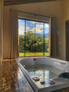 a large bath tub in a room with a large window at Pousada & Camping Nativos dos Canyons in Praia Grande