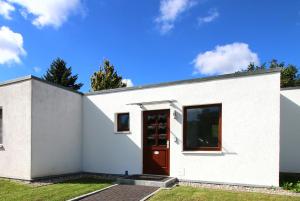 uma casa branca com uma porta vermelha em Ferienhaus Matrose em Warnemünde