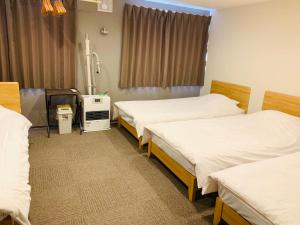 a hospital room with three beds and a window at Pension Berg in Niseko