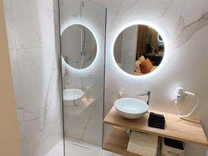 a bathroom with a sink and a shower with mirrors at ZEŪS apartment in Torremolinos +22 photos