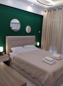 a bedroom with a large bed with a green wall at Domus Apartment - City Center in Veria