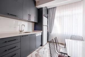 uma cozinha com armários cinzentos, um lavatório e uma janela em Modern Flat 5 min to Mahmutlar Beach in Alanya em Mahmutlar