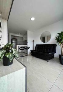 a living room with a black couch and some plants at Apartamento nuevo, central, hermosa vista. in Dosquebradas