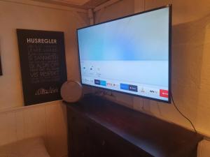 una grande TV a schermo piatto appesa a un muro di Koselig rom med stue i Bodø sentrum a Bodø