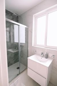 baño blanco con ducha y lavamanos en Spacious 3 bedroom in Sliema!, en Sliema