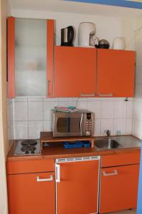 a kitchen with orange cabinets and a microwave at Ferienappartement K111 für 2-4 Personen in Strandnähe in Schönberg in Holstein