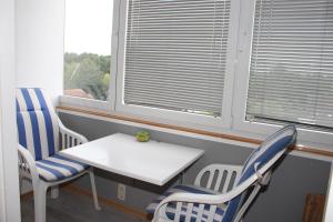 Zimmer mit 2 Stühlen, einem Tisch und 2 Fenstern in der Unterkunft Ferienwohnung Ostsee F414 in Schönberg in Holstein