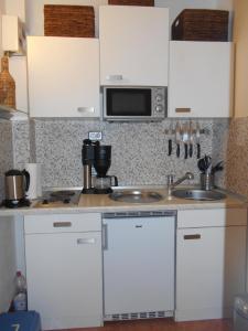 una cucina con mobili bianchi, un lavello e un microonde di Ferienappartement E417 für 2-4 Personen an der Ostsee a Schönberg in Holstein Altre 4 foto