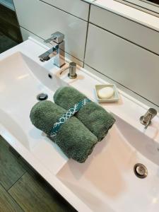 a green towel sitting on a bathroom sink at B&B Chambre Privative Chez L'habitant Sur La Route Des Vins Parking Box vélo in Issenheim