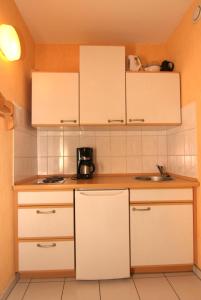eine kleine Küche mit weißen Schränken und einem Waschbecken in der Unterkunft Ferienwohnung F156 für 2-4 Personen an der Ostsee in Brasilien