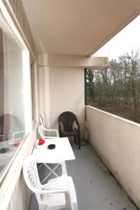 Elle comprend un petit balcon avec une table et des chaises blanches. dans l'établissement Ferienwohnung F156 für 2-4 Personen an der Ostsee, à Brasilien