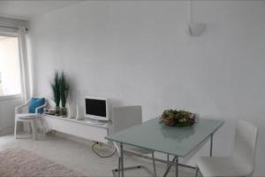 Sala de estar blanca con mesa y TV en Ferienwohnung K1405 für 2-4 Personen mit Ostseeblick, en Schönberg in Holstein