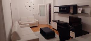 een woonkamer met witte meubels en een televisie bij Apartman Centar 1 in Bijeljina