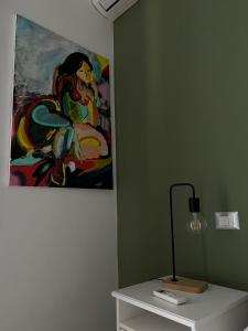 a table with a lamp and a painting on the wall at La Veronica Apartment in Naples
