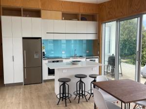 a kitchen with white cabinets and a table and chairs at Whatuwhiwhi View in Karikari Peninsula