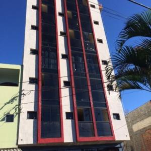 a tall building with many windows and a palm tree at Portal Palace Hotel in Aparecida