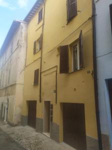 a yellow building with doors and windows on a street at Il Vicoletto Holiday Rooms in Spoleto