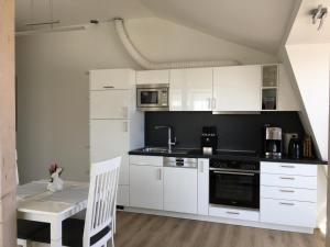 a kitchen with white cabinets and a table and a sink at Seeblick 2 in Dahme
