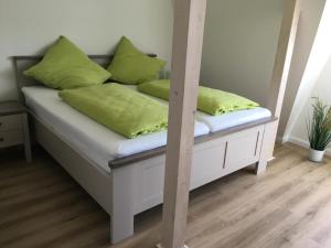 a bed with green pillows on it in a room at Seeblick 2 in Dahme