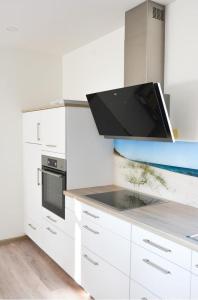 a kitchen with white cabinets and a black microwave at Zur Strandwiese W6 in Dahme