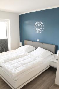 a white bed in a room with a blue wall at Zur Strandwiese W6 in Dahme