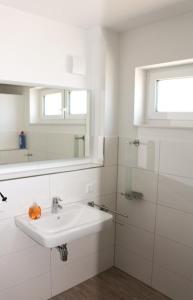 een witte badkamer met een wastafel en een spiegel bij Zur Strandwiese W6 in Dahme
